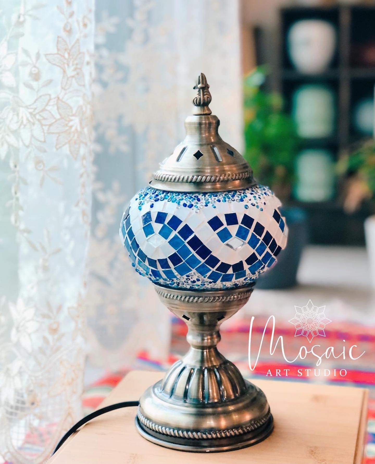 Turkish mosaic lamp with blue and white glass tiles on brass base, displayed on wooden surface