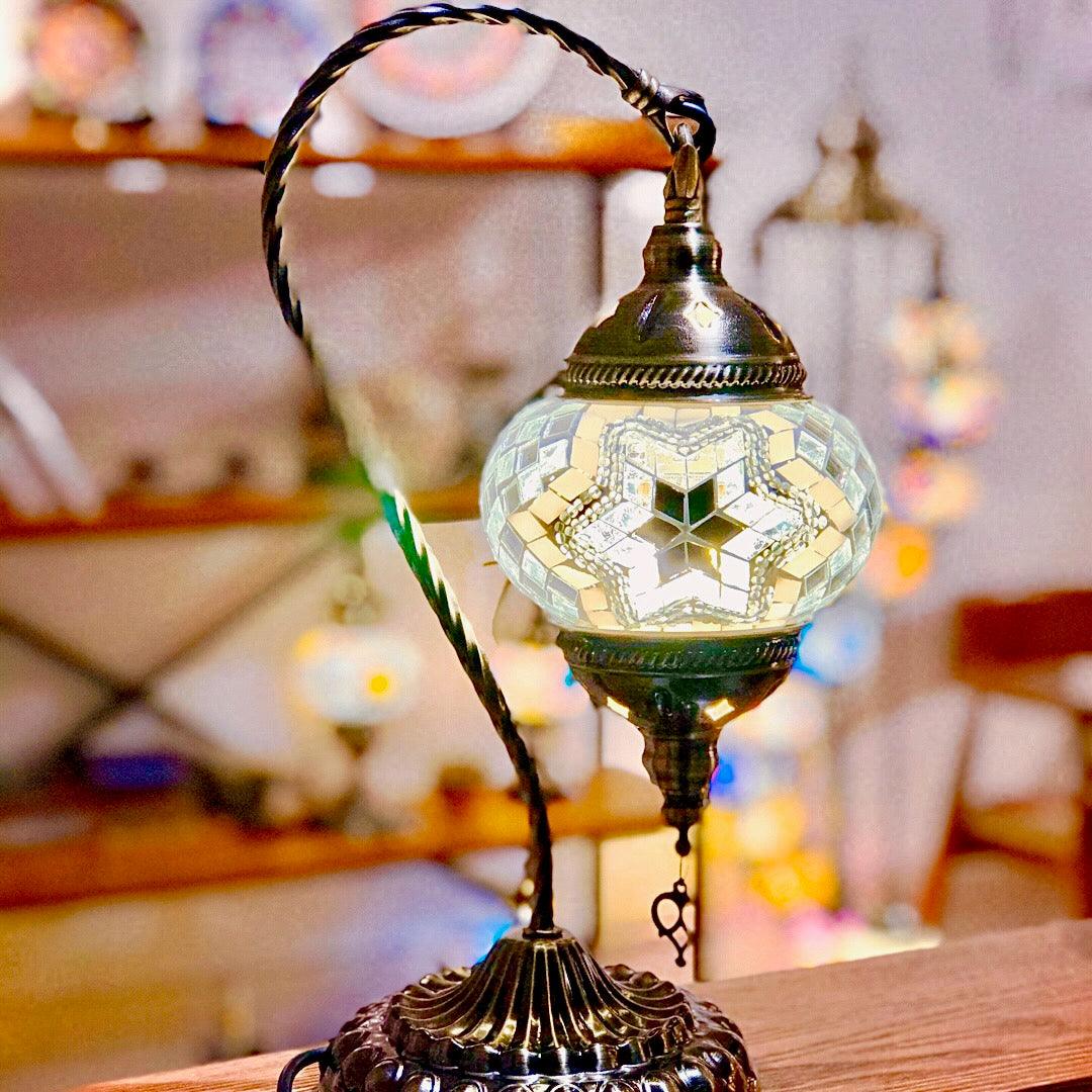 Turkish mosaic lamp with intricate star-patterned glass on ornate metal stand, glowing warmly indoors