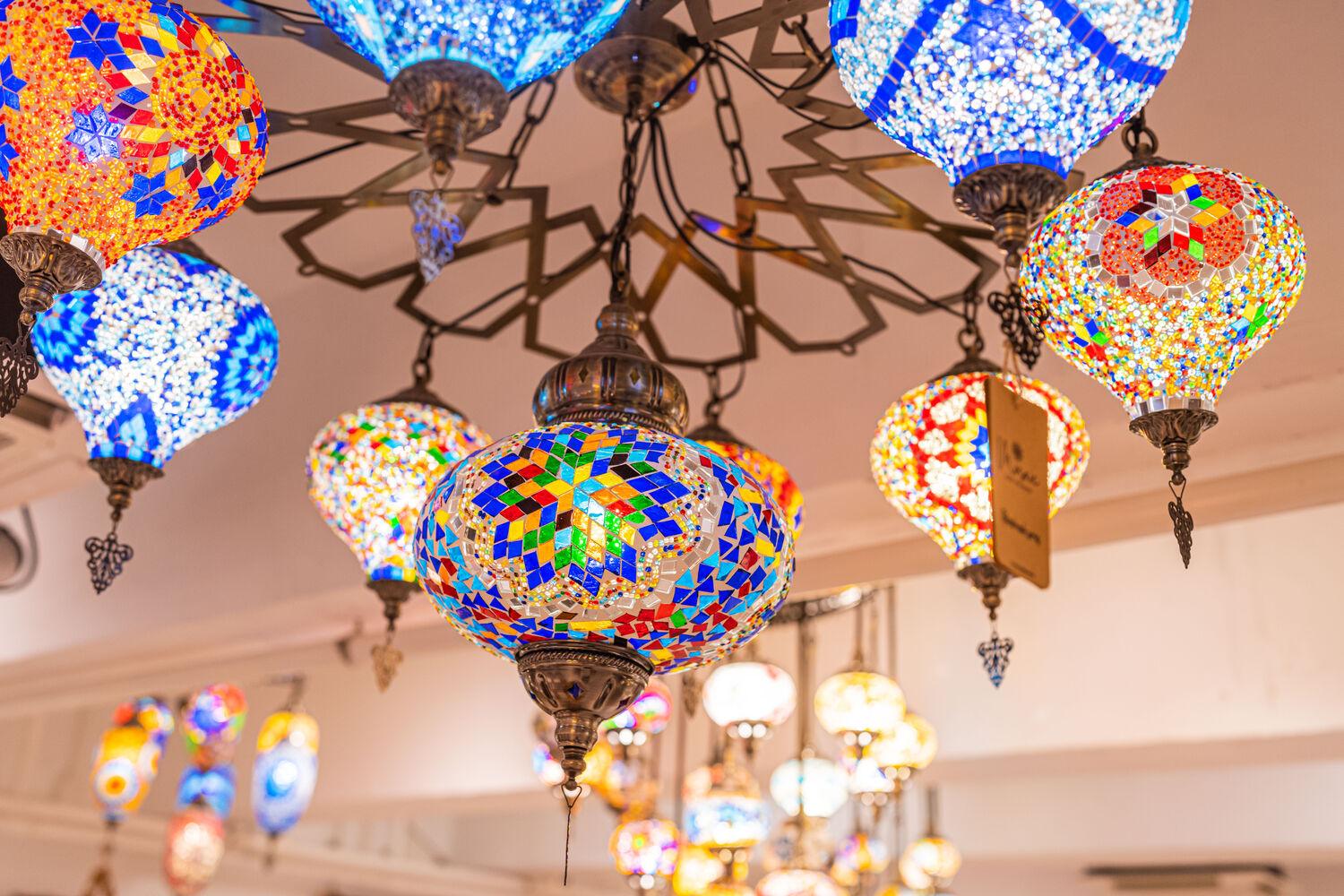 Colorful mosaic Turkish lamps hanging from ceiling in bright indoor market
