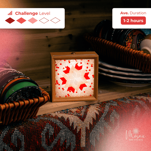 Lit mosaic lamp with red and white star pattern on wooden shelf near colorful fabric and dishes