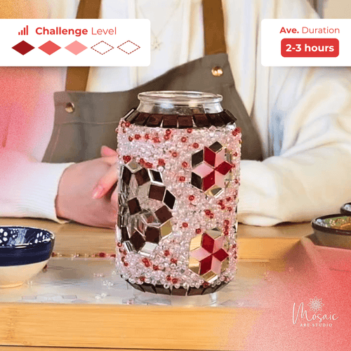 Hand holding mosaic lamp jar decorated with red and silver tiles and beads on wooden table