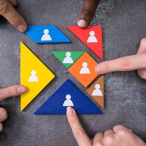 Hands assembling colorful puzzle pieces with person icons symbolizing team collaboration and engagement