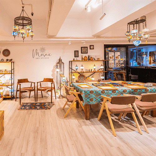 Cozy mosaic art studio with wooden chairs, mosaic lamps, patterned tablecloth, and decorative shelves