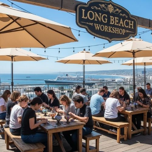 People crafting mosaic lamps outdoors at Long Beach Workshop with umbrellas and ocean view