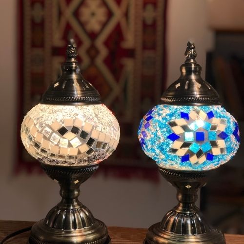 Two ornate Turkish mosaic lamps with bronze bases and colorful glass tile designs on a wooden surface