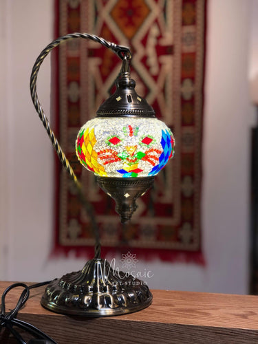 Turkish mosaic lamp with colorful glass pieces on metal stand, traditional rug background