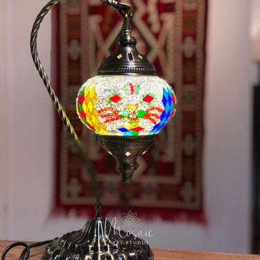 Turkish mosaic lamp with colorful glass pieces on metal stand, traditional rug background