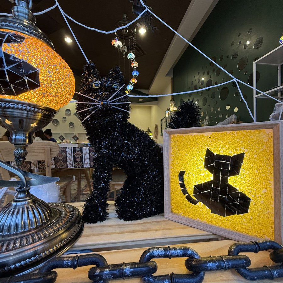 Black cat mosaic globe lamp and glowing yellow black cat light box together in a Halloween window display