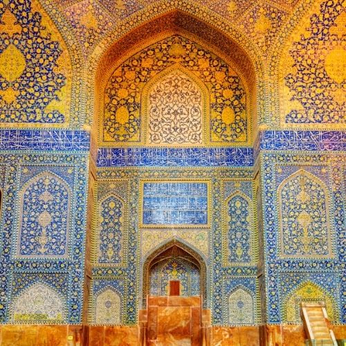 Intricate Islamic mosaic art with blue and gold geometric patterns and Arabic calligraphy on mosque walls