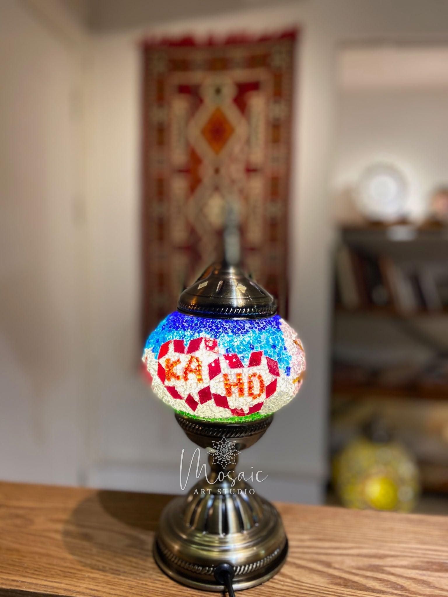Colorful Turkish mosaic lamp with 'KAHO' text on wooden table in cozy room
