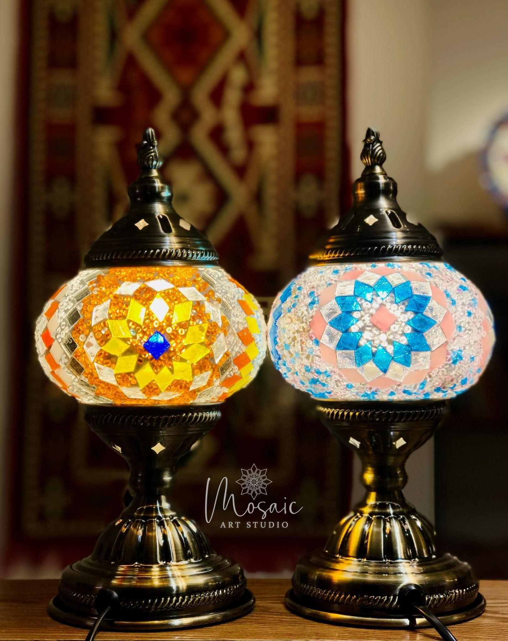 Pair of Turkish mosaic lamps with colorful glass beads in orange and blue patterns on a dark metal base