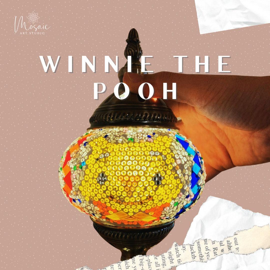 Hand holding a colorful Turkish mosaic lamp featuring a Winnie the Pooh design with bright sequins