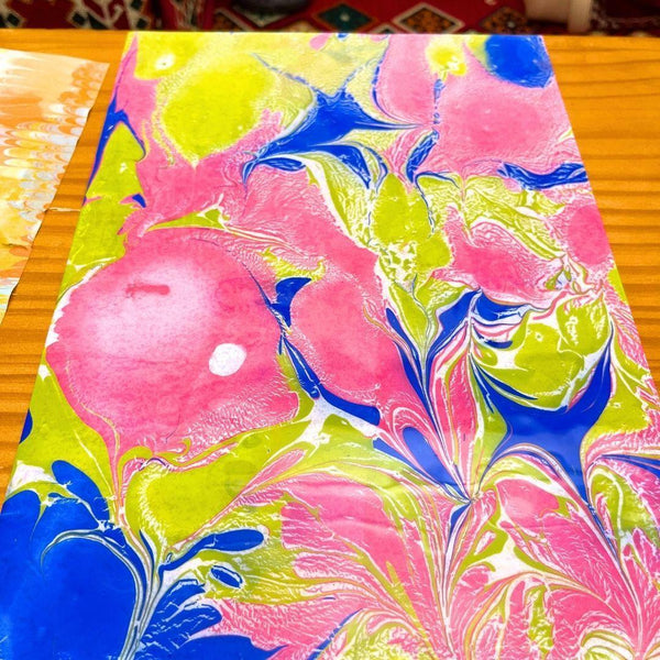 Abstract marble painting with pink, blue, and yellow swirls on wooden surface