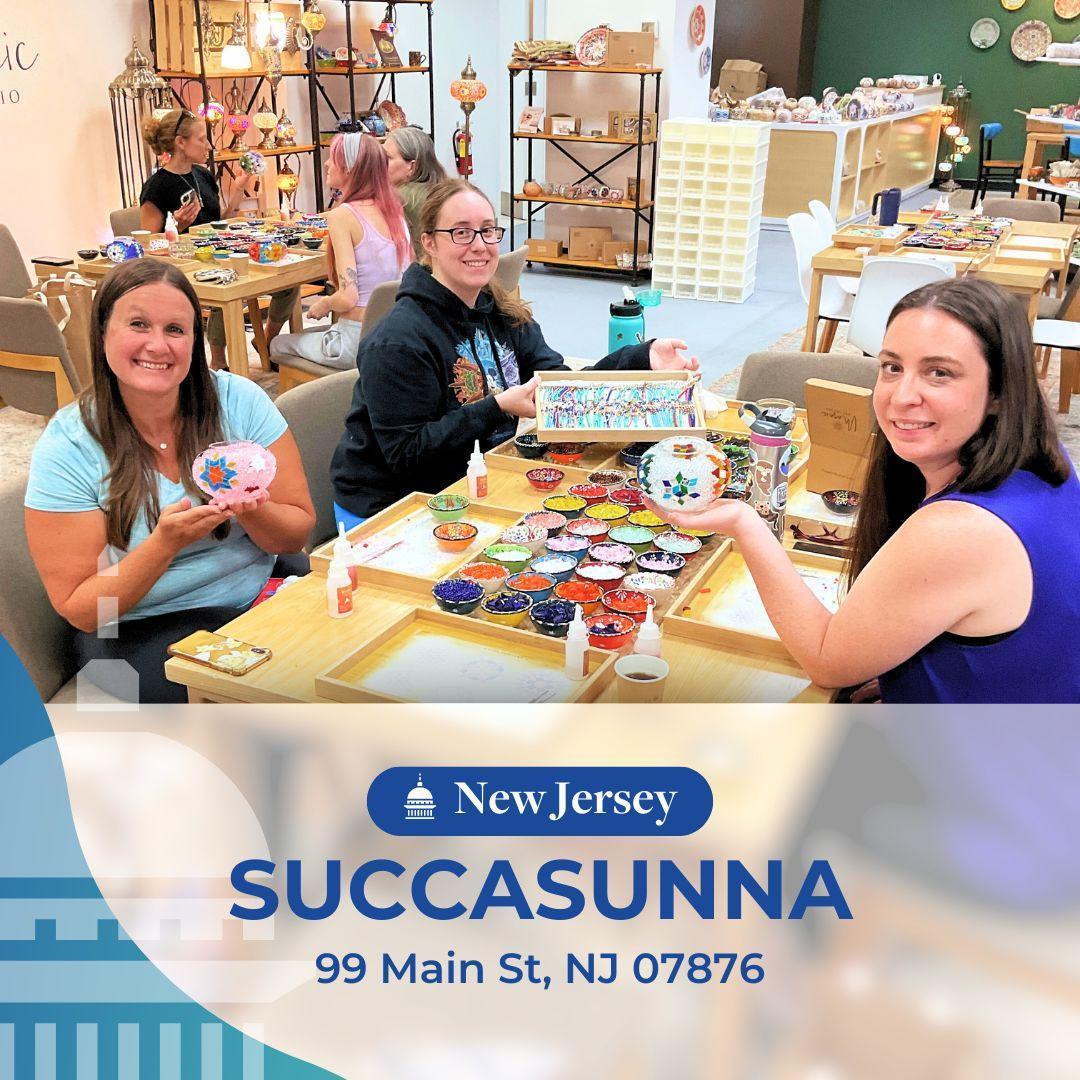 Three women smiling and crafting mosaic art with colorful tiles at a Succasunna New Jersey art studio