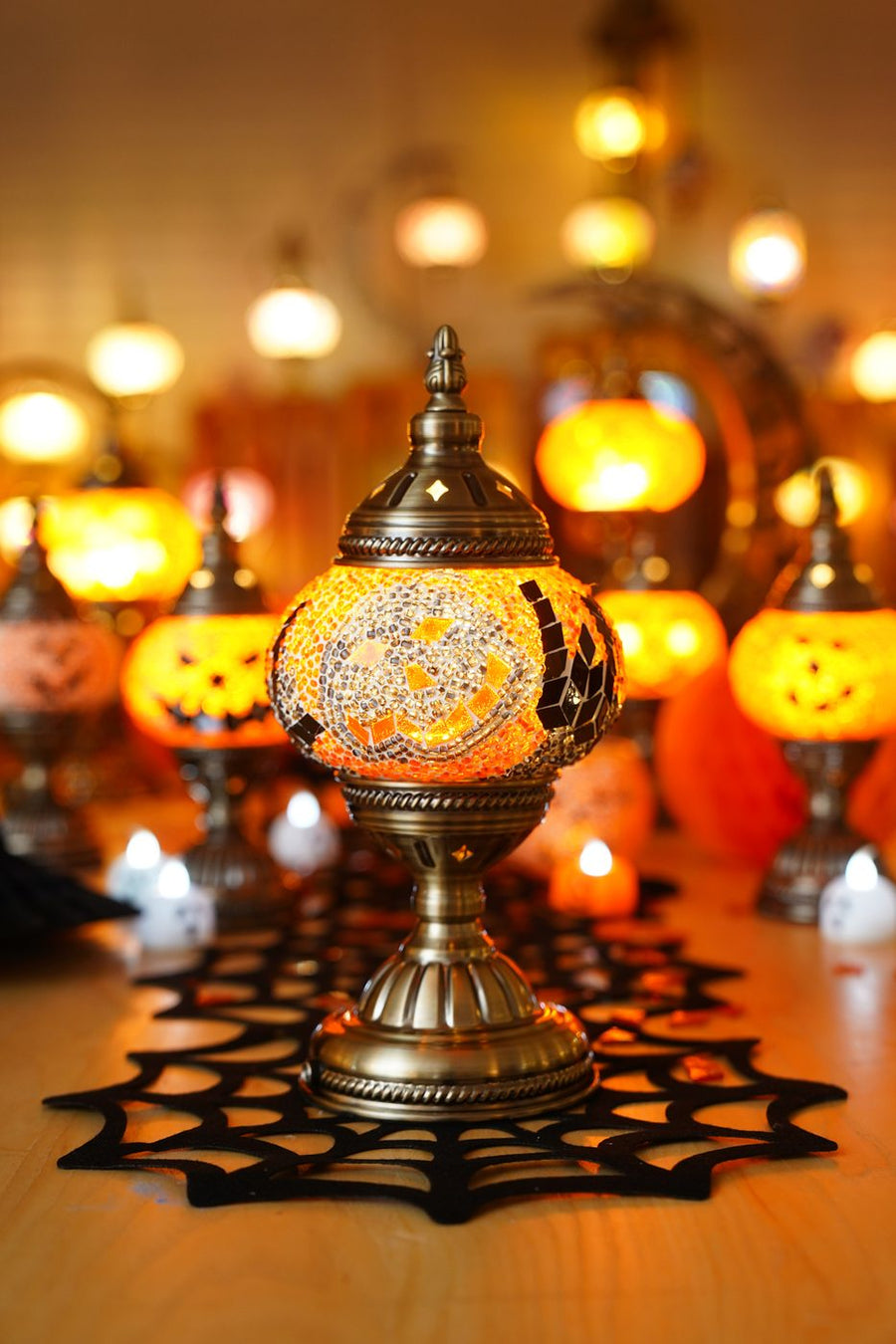 Handmade Halloween mosaic lamp glowing among candles