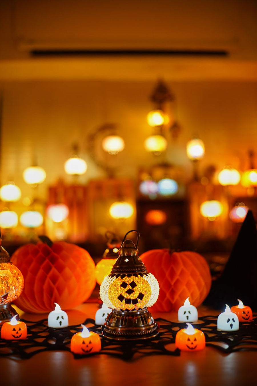 Handmade Halloween mosaic lamp glowing among candles