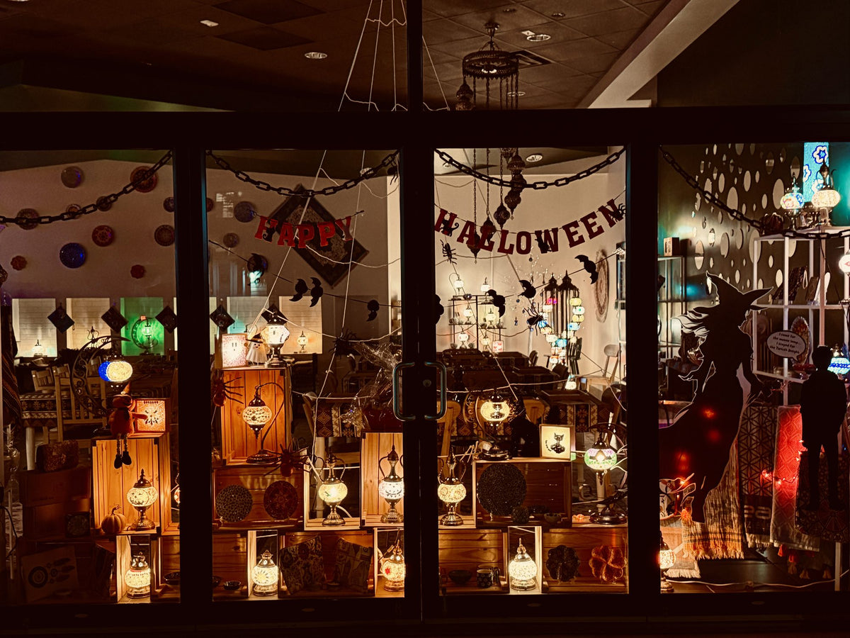 A Mosaic Art Studio decorated for Halloween, with glowing mosaic lamps, bats and a witch silhouette in the window