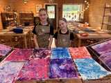 Students standing behind a table covered with finished Ebru water-marbled papers in pink, purple and blue