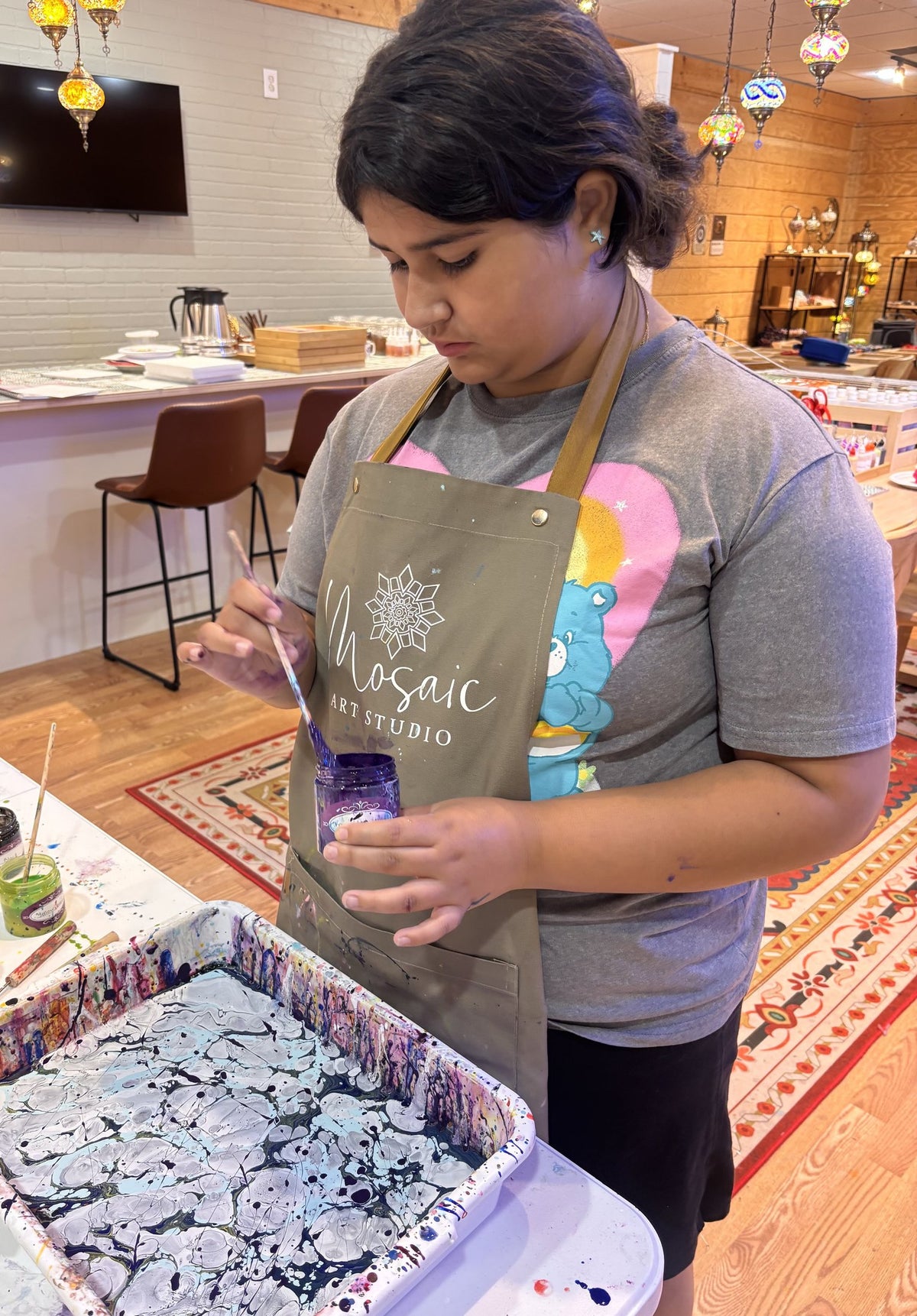 Student swirling paint on the surface of an Ebru water-marbling tray