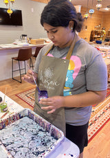 Student swirling paint on the surface of an Ebru water-marbling tray