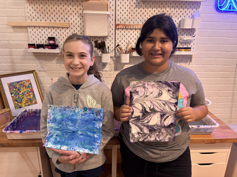 Two students holding up their finished Ebru marbled artworks