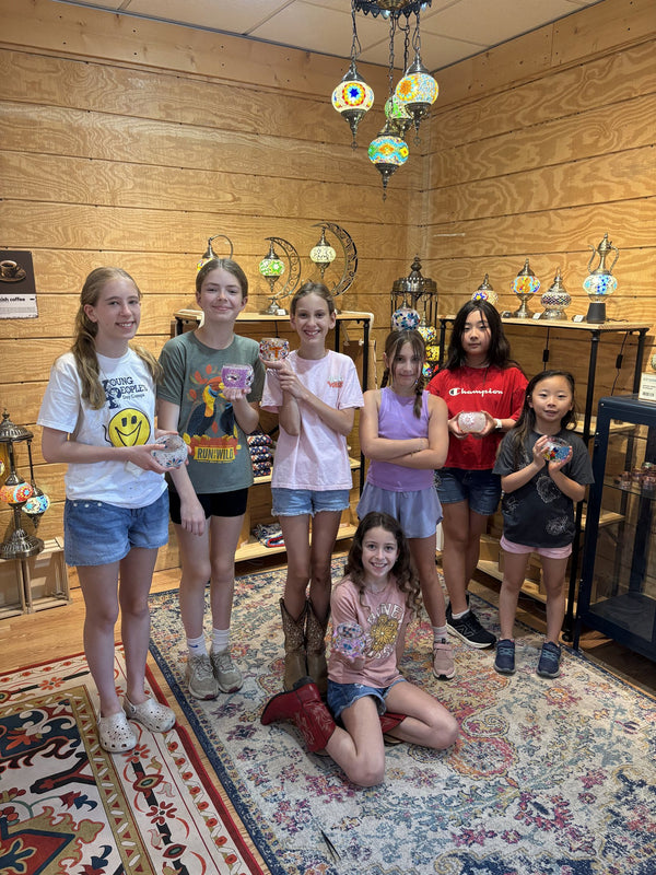 Group of students holding the mosaic lamps and artwork they made during the program