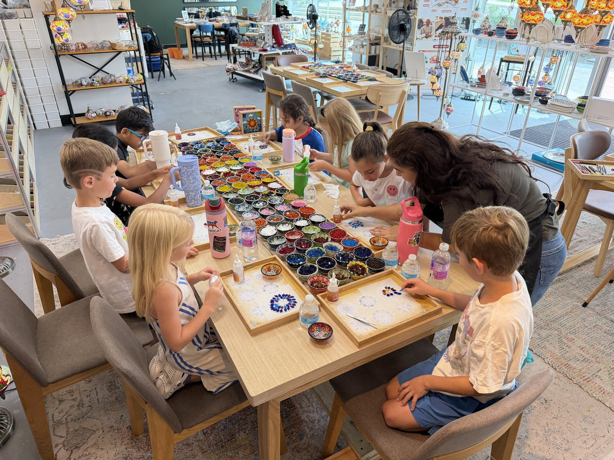 Children arranging coloured glass tiles on mosaic trays during an after-school mosaic class