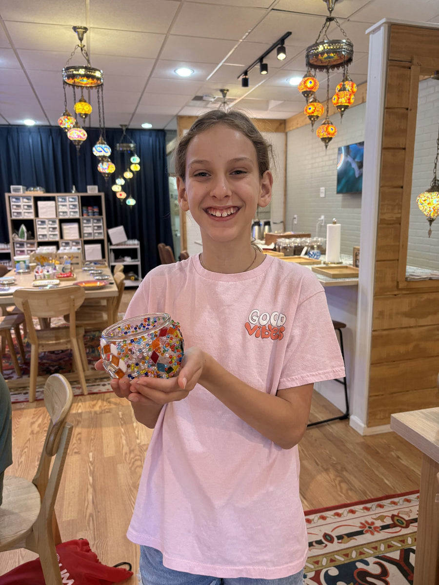 Student holding a finished Turkish mosaic lamp shade decorated with coloured glass