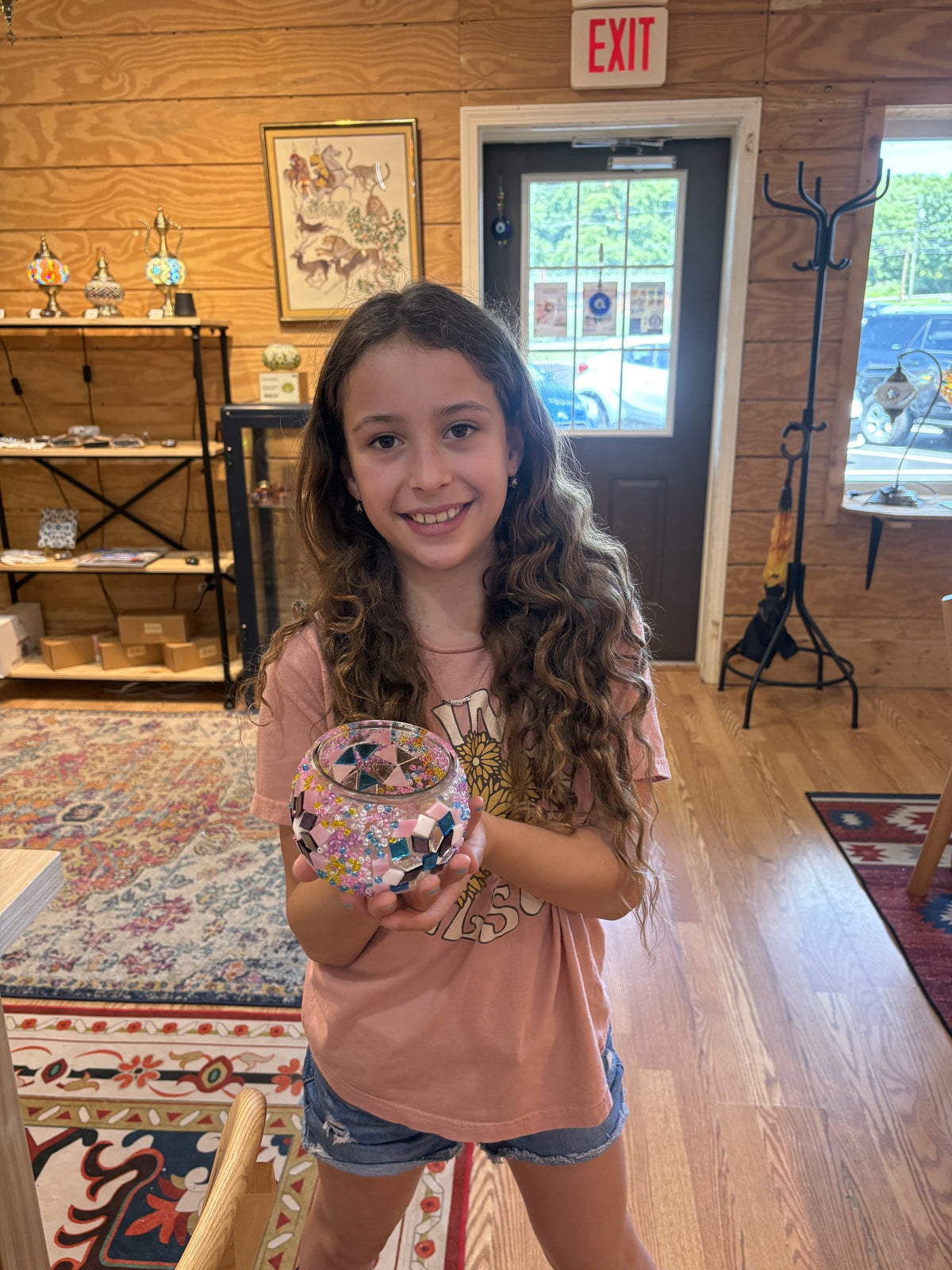 Student holding up a finished mosaic piece she made in class