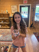 Student holding up a finished mosaic piece she made in class
