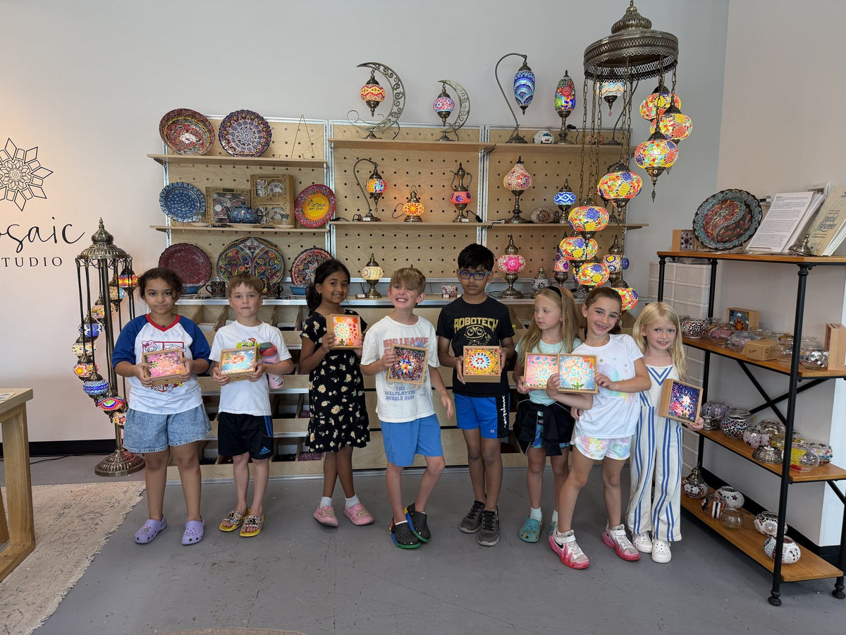 Group of students with their artwork in front of the Turkish mosaic lamp display at the Voorhees studio