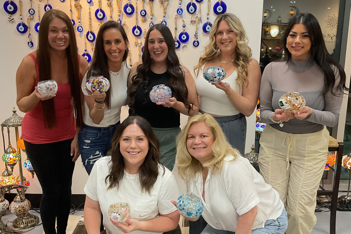 A group of friends with their mosaic lamps in front of the evil-eye wall at Mosaic Art Studio Voorhees