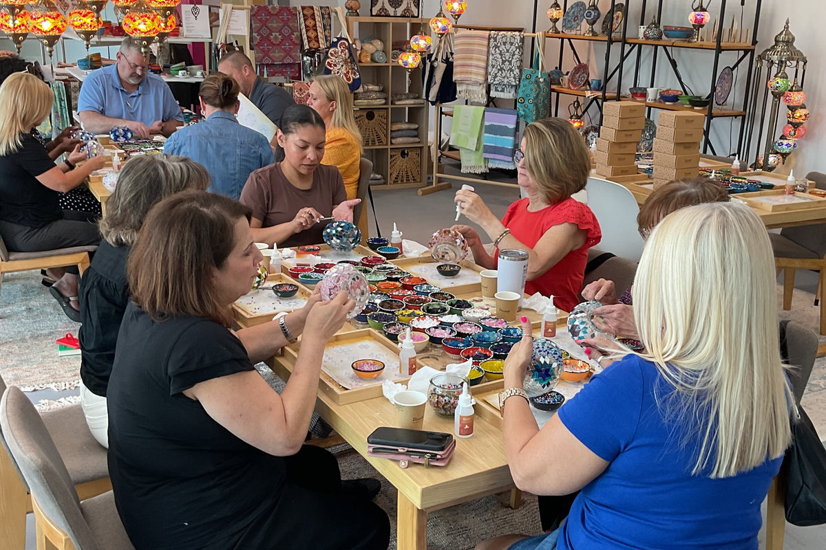 A mosaic lamp workshop at Mosaic Art Studio in Voorhees, NJ: guests at long tables making Turkish mosaic lamps, with lanterns and shelves of lamps behind them
