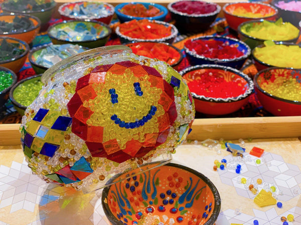 A smiley face in yellow and red. Handmade with love at a Mosaic Art Studio workshop.