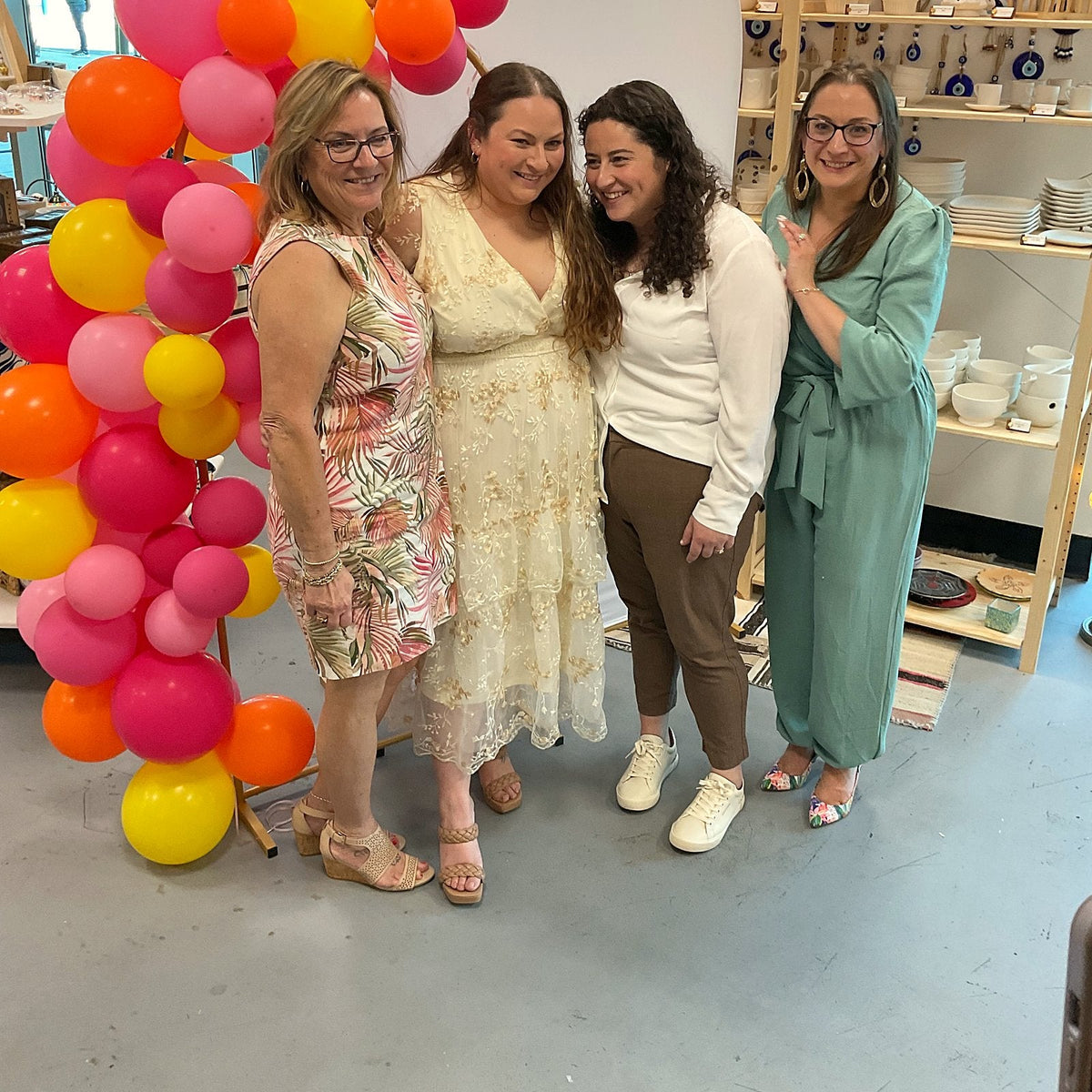 Friends celebrating beside a balloon arch at a mosaic workshop