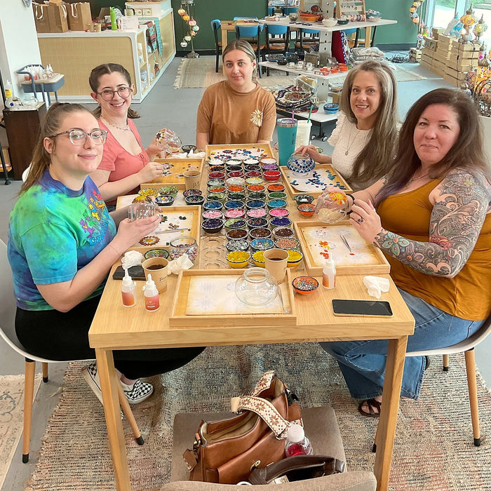 Friends gathered at a workshop table making mosaic lamps