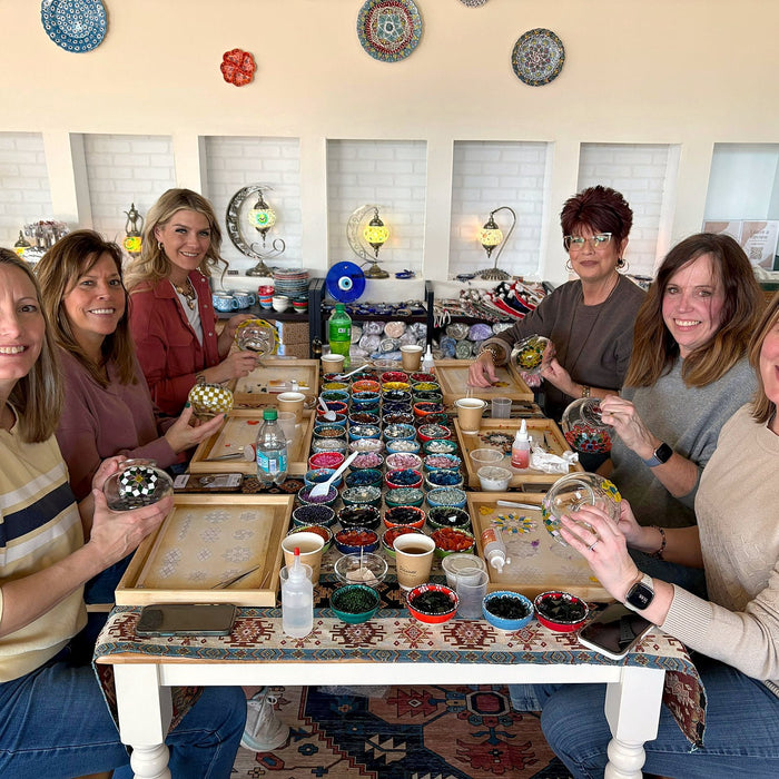Group of friends celebrating around a mosaic lamp workshop table