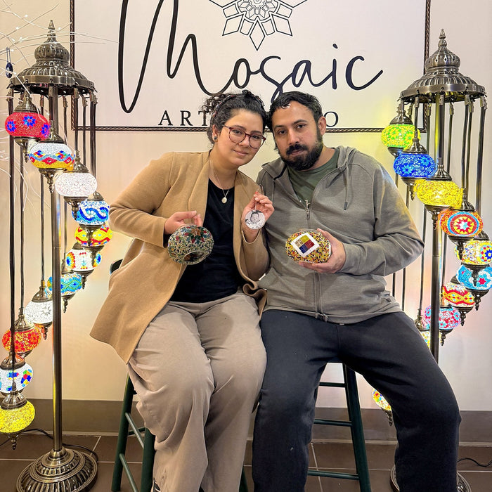 Couple sitting together with the mosaic lamps they made