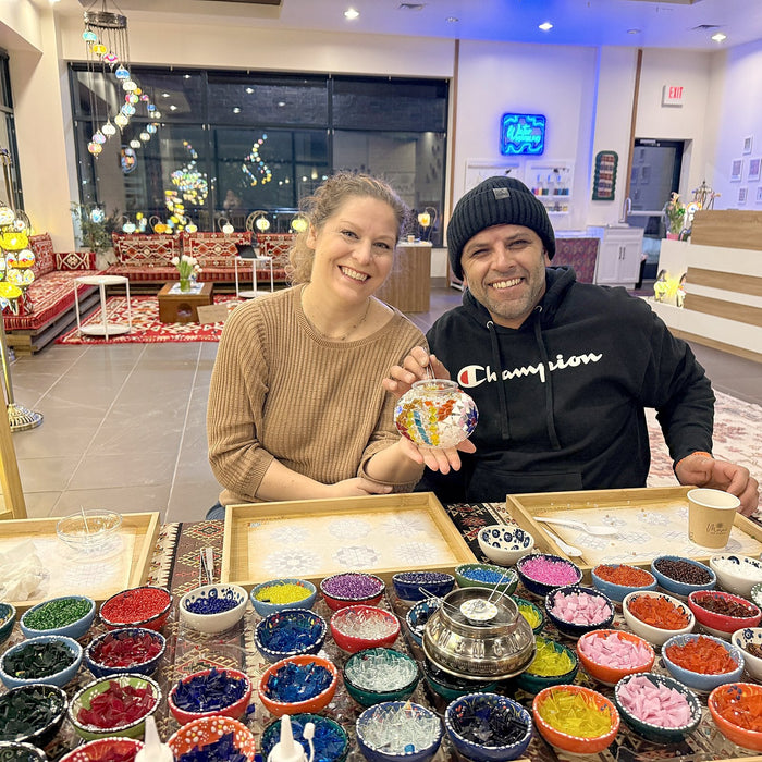 Couple holding up their mosaic lamp globes at the workshop table