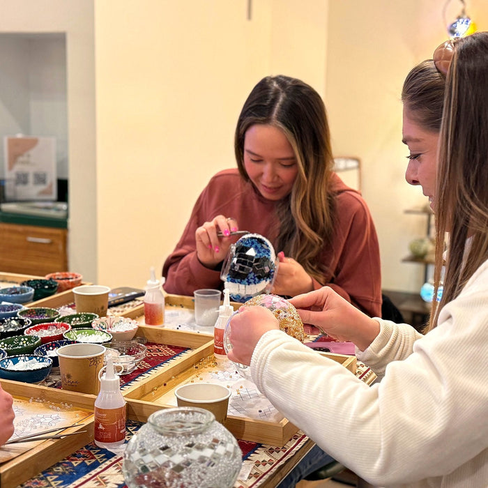 Two friends working on their mosaic lamps side by side