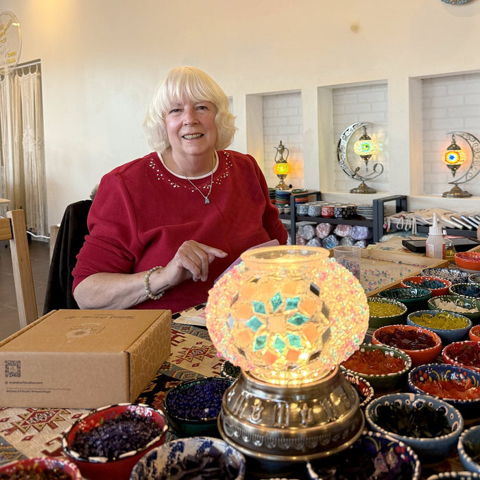 Guest with her lit mosaic table lamp at the workshop