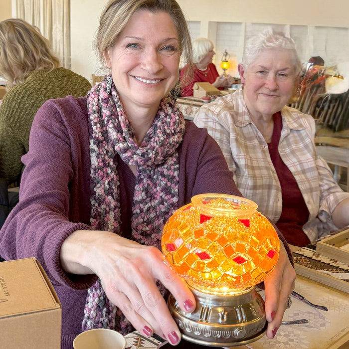 Guest holding her glowing orange mosaic lamp beside a friend