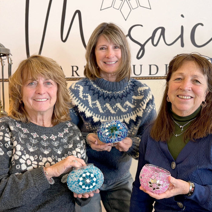 Three friends smiling with their finished mosaic lamps