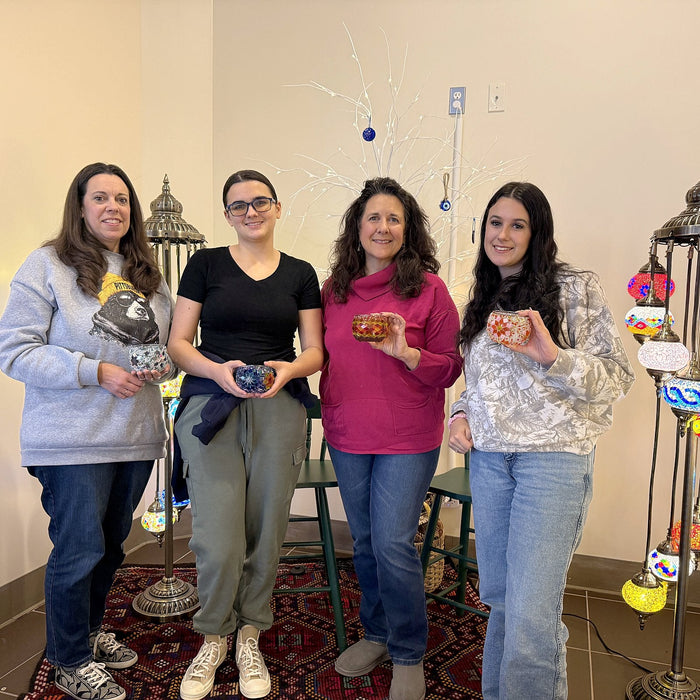 Four friends standing with the mosaic lamps they made