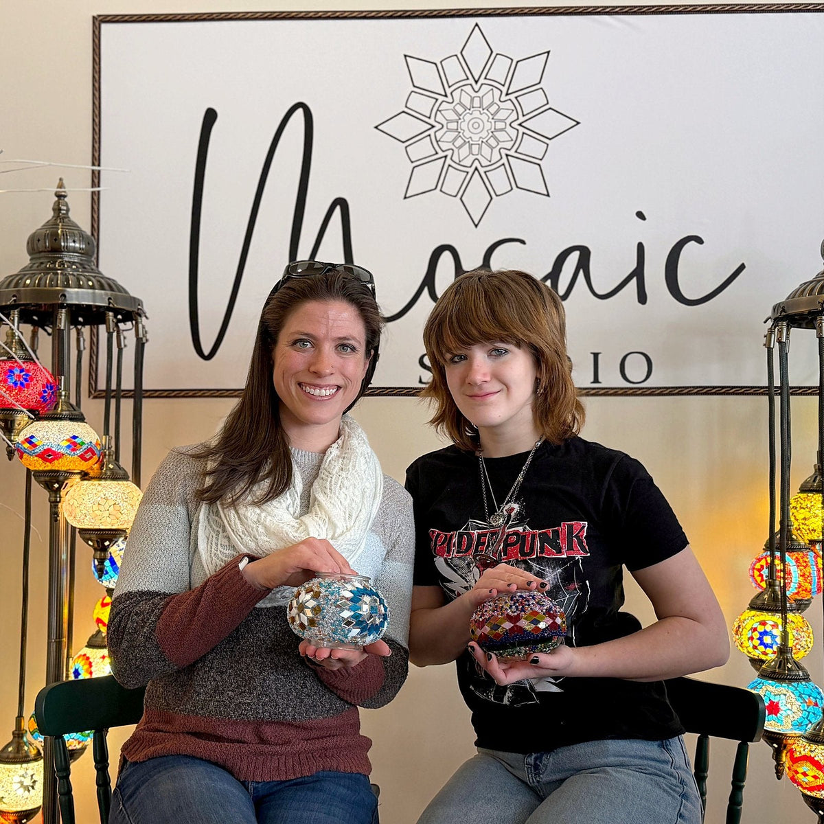 Mom and teenage daughter holding the mosaic lamps they made