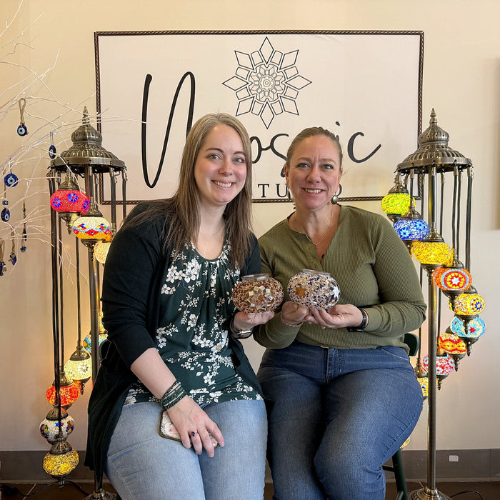 Mother and daughter showing their mosaic lamps between glowing lamp stands