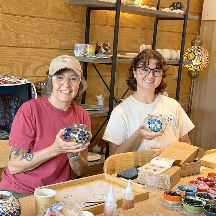 Mother and daughter at a workshop table with their mosaic lamps