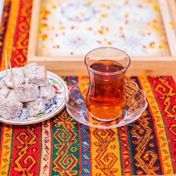Turkish tea in a tulip glass served with Turkish delight beside a mosaic design tray