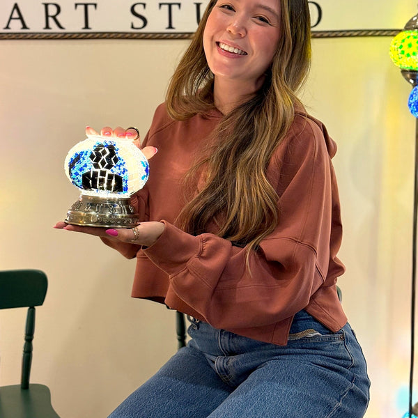 Guest laughing as she holds the mosaic lamp she made