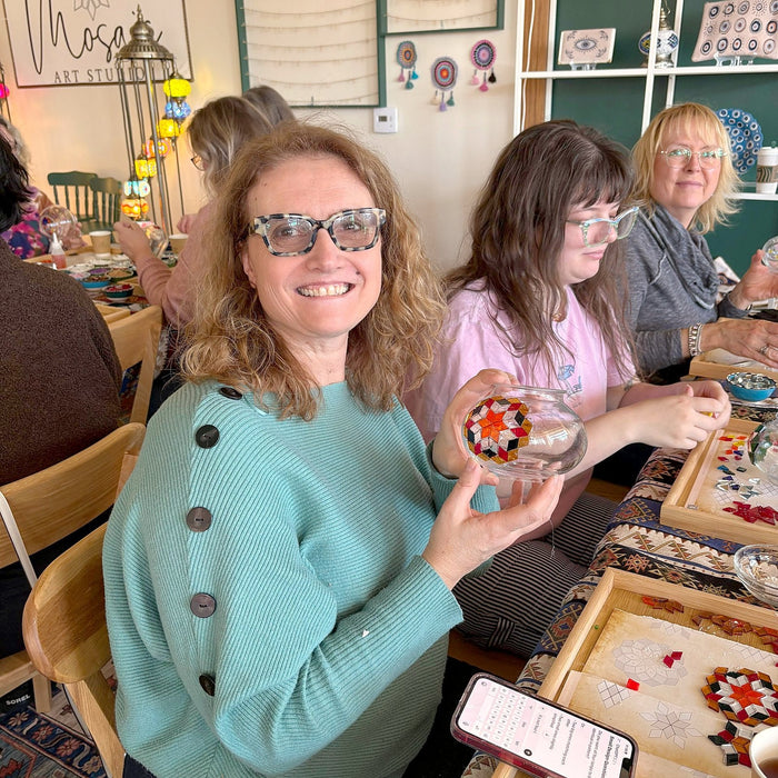 Guest smiling while showing her mosaic lamp at the table